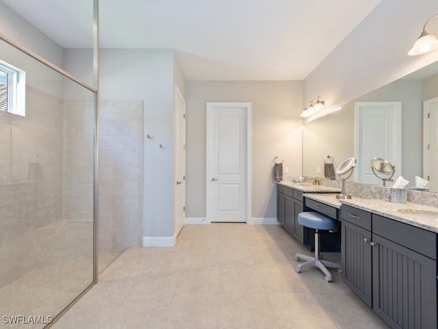 bathroom with a tile shower, vanity, and tile patterned floors