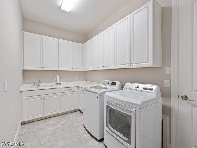 clothes washing area with washing machine and dryer, sink, and cabinets