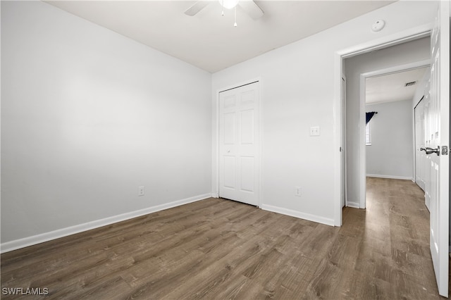 unfurnished bedroom with dark wood-type flooring, ceiling fan, and a closet