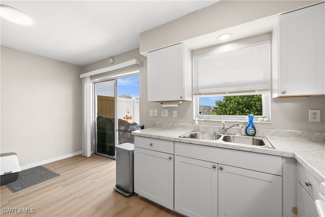 kitchen featuring white cabinetry, a healthy amount of sunlight, light hardwood / wood-style flooring, and sink