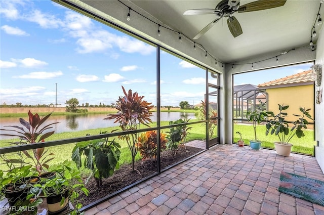 unfurnished sunroom featuring ceiling fan and a water view