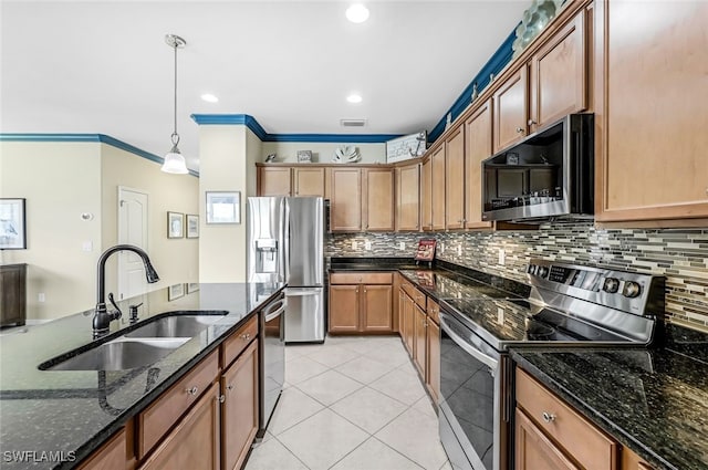 kitchen with sink, light tile patterned flooring, dark stone counters, hanging light fixtures, and appliances with stainless steel finishes