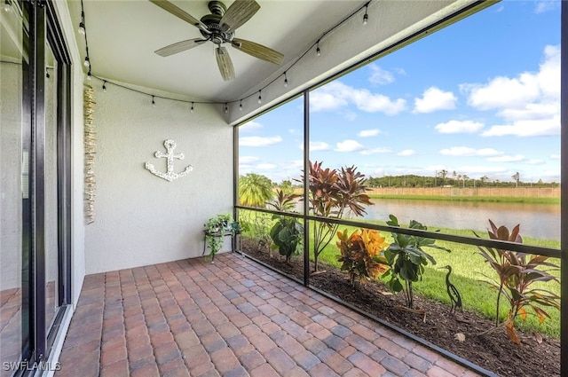 unfurnished sunroom with ceiling fan and a water view