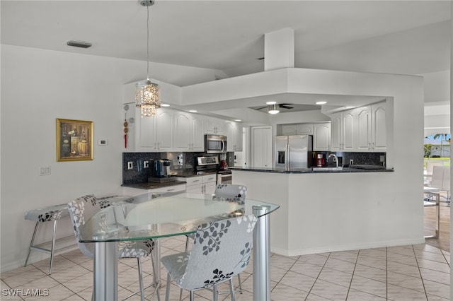 kitchen featuring vaulted ceiling, stainless steel appliances, white cabinetry, kitchen peninsula, and ceiling fan