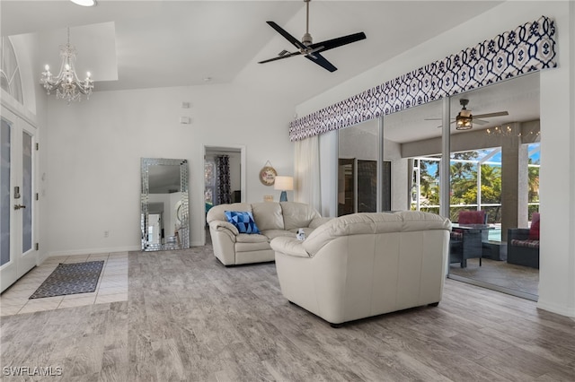 living room with ceiling fan with notable chandelier, high vaulted ceiling, and light hardwood / wood-style floors