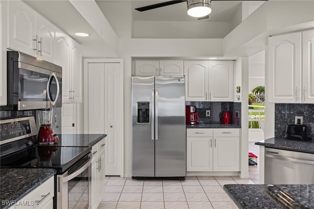 kitchen with white cabinets, dark stone counters, stainless steel appliances, and ceiling fan