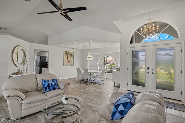 living room featuring ceiling fan with notable chandelier, french doors, high vaulted ceiling, and light hardwood / wood-style flooring