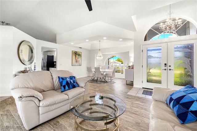 living room with french doors, vaulted ceiling, a notable chandelier, and hardwood / wood-style flooring