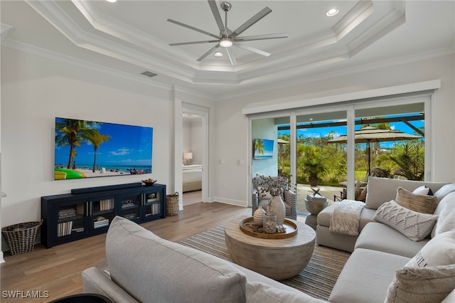 living room featuring ceiling fan, crown molding, and a tray ceiling