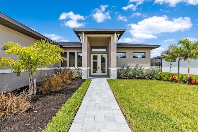 view of exterior entry with french doors and a lawn