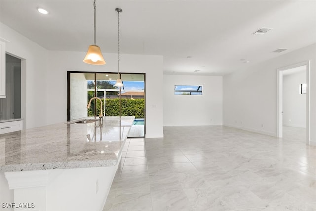 kitchen with pendant lighting, light stone countertops, and sink