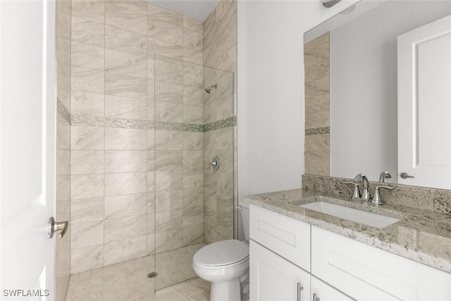 bathroom featuring vanity, toilet, and tiled shower