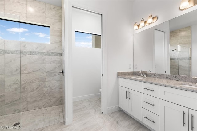 bathroom featuring a tile shower, vanity, and toilet