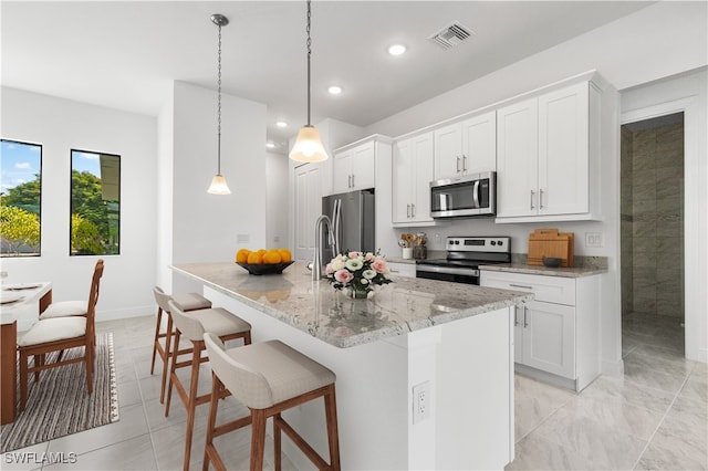 kitchen featuring pendant lighting, white cabinets, a center island with sink, and appliances with stainless steel finishes