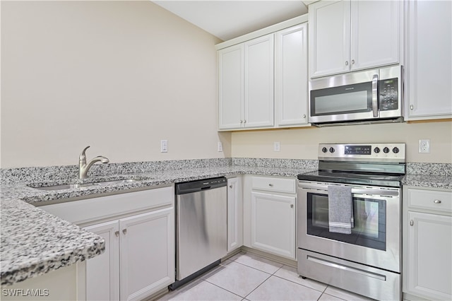 kitchen featuring light tile patterned floors, appliances with stainless steel finishes, sink, light stone counters, and white cabinets