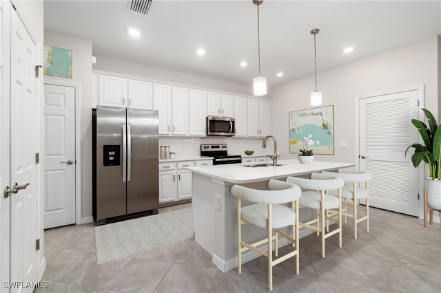 kitchen with sink, white cabinetry, hanging light fixtures, stainless steel appliances, and a center island with sink