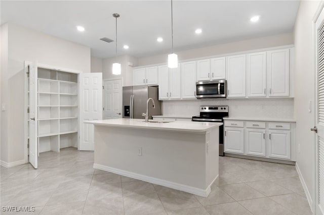 kitchen with stainless steel appliances, white cabinetry, and a center island with sink