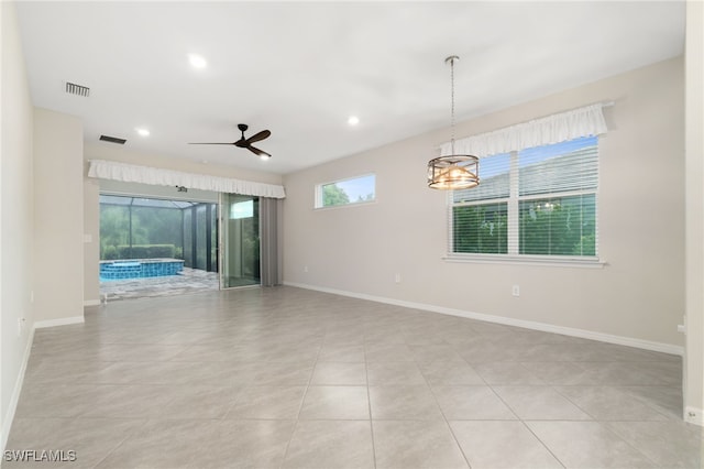 tiled spare room with plenty of natural light and ceiling fan with notable chandelier