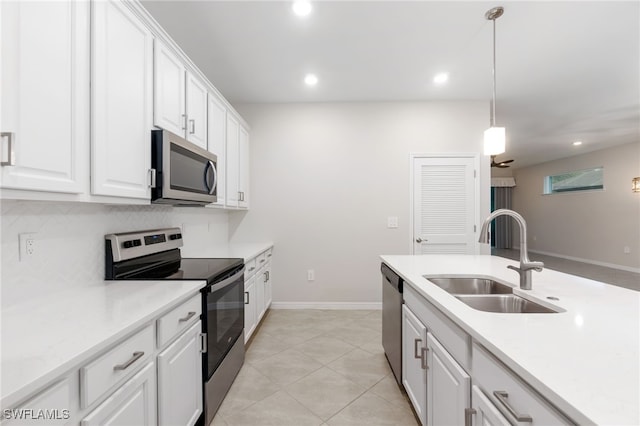 kitchen with sink, light tile patterned floors, appliances with stainless steel finishes, white cabinets, and decorative light fixtures