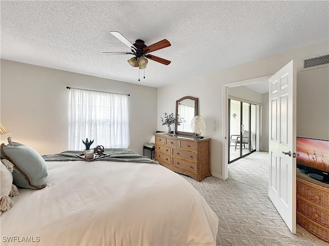 bedroom with light carpet, a textured ceiling, visible vents, and a ceiling fan