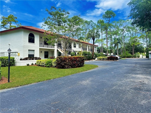 exterior space featuring a tile roof, a front lawn, and stucco siding