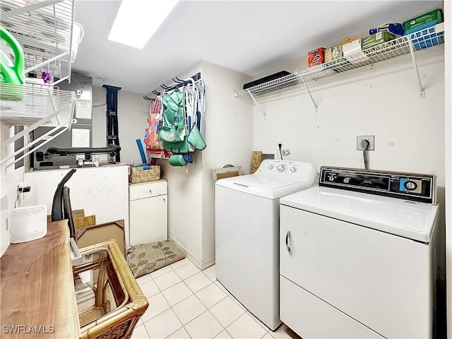 washroom with a skylight, laundry area, washer and clothes dryer, and light tile patterned floors