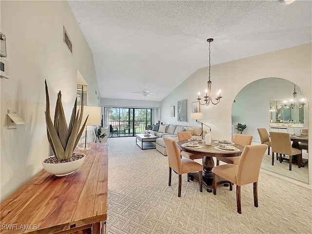 dining space featuring light carpet, visible vents, arched walkways, a textured ceiling, and ceiling fan with notable chandelier