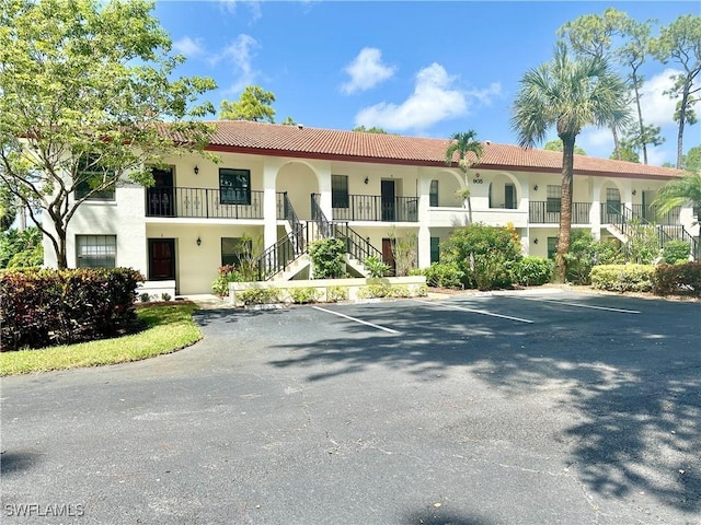 view of property featuring stairs and uncovered parking