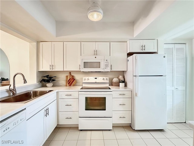 kitchen featuring white appliances, white cabinetry, light countertops, and a sink