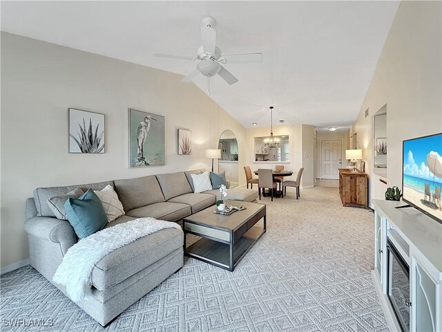 living area featuring arched walkways, lofted ceiling, light colored carpet, baseboards, and ceiling fan with notable chandelier