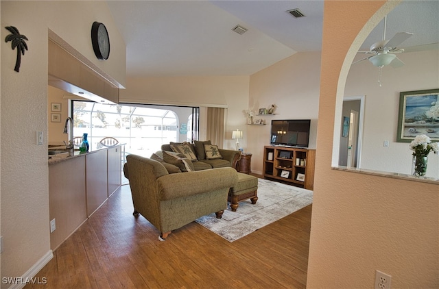 living room featuring lofted ceiling, ceiling fan, sink, and wood-type flooring