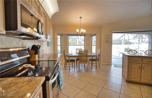 kitchen with light tile patterned floors, stainless steel appliances, a notable chandelier, pendant lighting, and tasteful backsplash