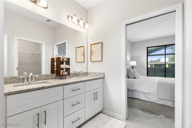 ensuite bathroom featuring double vanity, baseboards, a sink, and ensuite bathroom