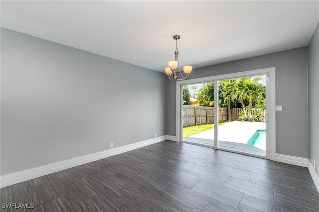 spare room with dark wood-type flooring and a chandelier