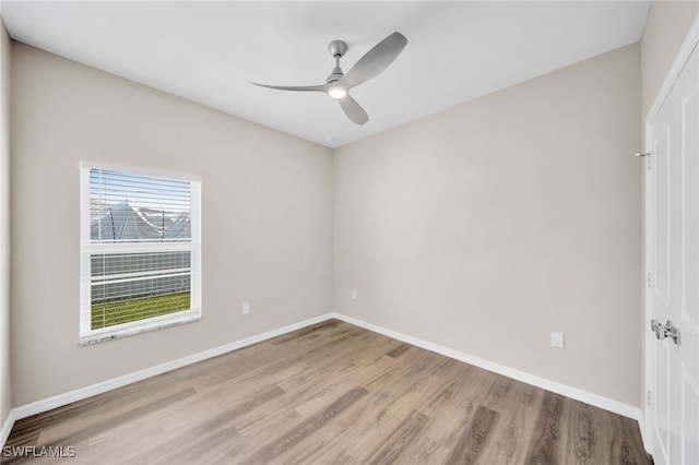 empty room with a wealth of natural light, wood-type flooring, and ceiling fan