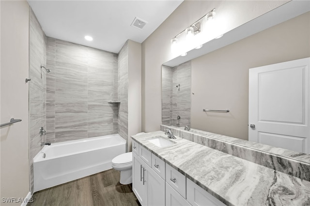 full bathroom featuring tiled shower / bath combo, vanity, toilet, and hardwood / wood-style flooring