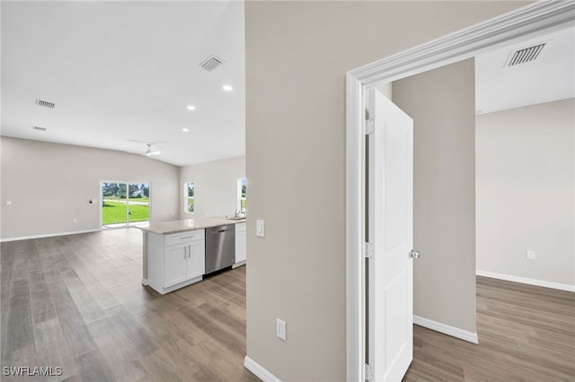 kitchen featuring white cabinetry, stainless steel dishwasher, hardwood / wood-style flooring, and lofted ceiling