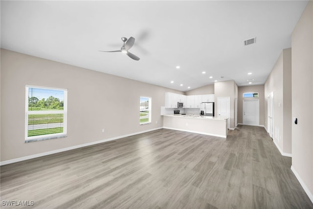 unfurnished living room with ceiling fan, a wealth of natural light, hardwood / wood-style flooring, and vaulted ceiling