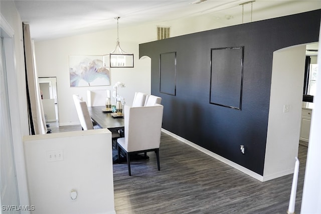 dining area with vaulted ceiling, a notable chandelier, and dark hardwood / wood-style flooring