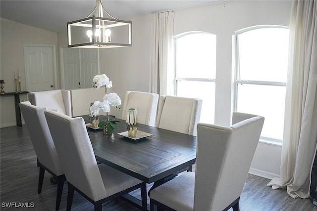 dining area with dark wood-type flooring, vaulted ceiling, and a chandelier