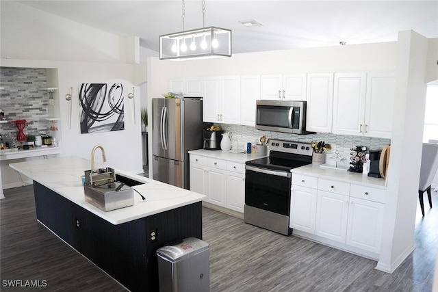 kitchen featuring hanging light fixtures, hardwood / wood-style flooring, appliances with stainless steel finishes, a kitchen island, and decorative backsplash