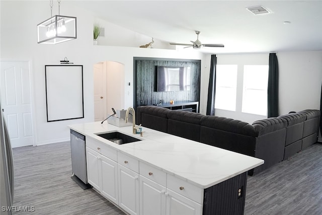 kitchen featuring a kitchen island with sink, ceiling fan with notable chandelier, sink, stainless steel dishwasher, and white cabinets