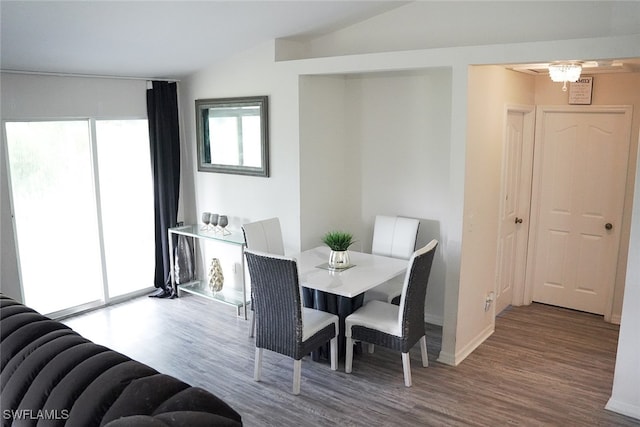 dining space with vaulted ceiling and hardwood / wood-style flooring