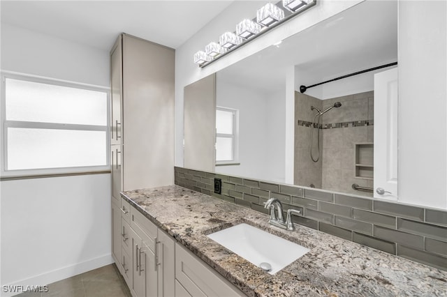 bathroom featuring decorative backsplash, tile patterned floors, vanity, and tiled shower