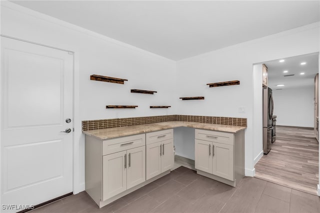 kitchen featuring stainless steel fridge, light hardwood / wood-style flooring, light stone countertops, ornamental molding, and white cabinetry