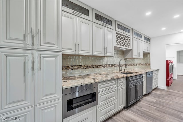 kitchen with white cabinets, sink, stainless steel appliances, light wood-type flooring, and decorative backsplash