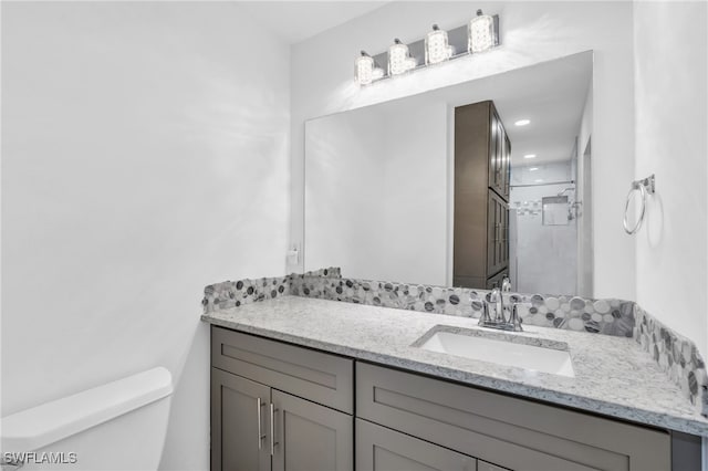 bathroom with vanity, a shower, and toilet