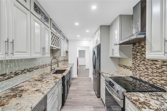 kitchen featuring stainless steel appliances, wall chimney exhaust hood, white cabinets, and sink