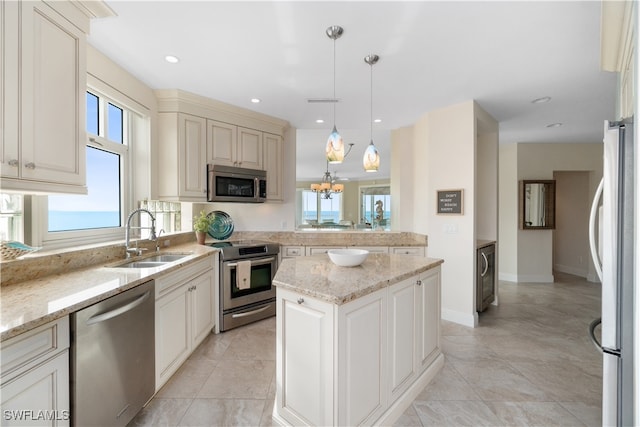 kitchen with sink, decorative light fixtures, stainless steel appliances, light stone countertops, and a wealth of natural light