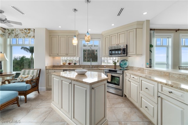 kitchen with pendant lighting, stainless steel appliances, ceiling fan, and a healthy amount of sunlight